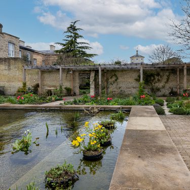A large square pond with plant pots that have flowers in them in it.